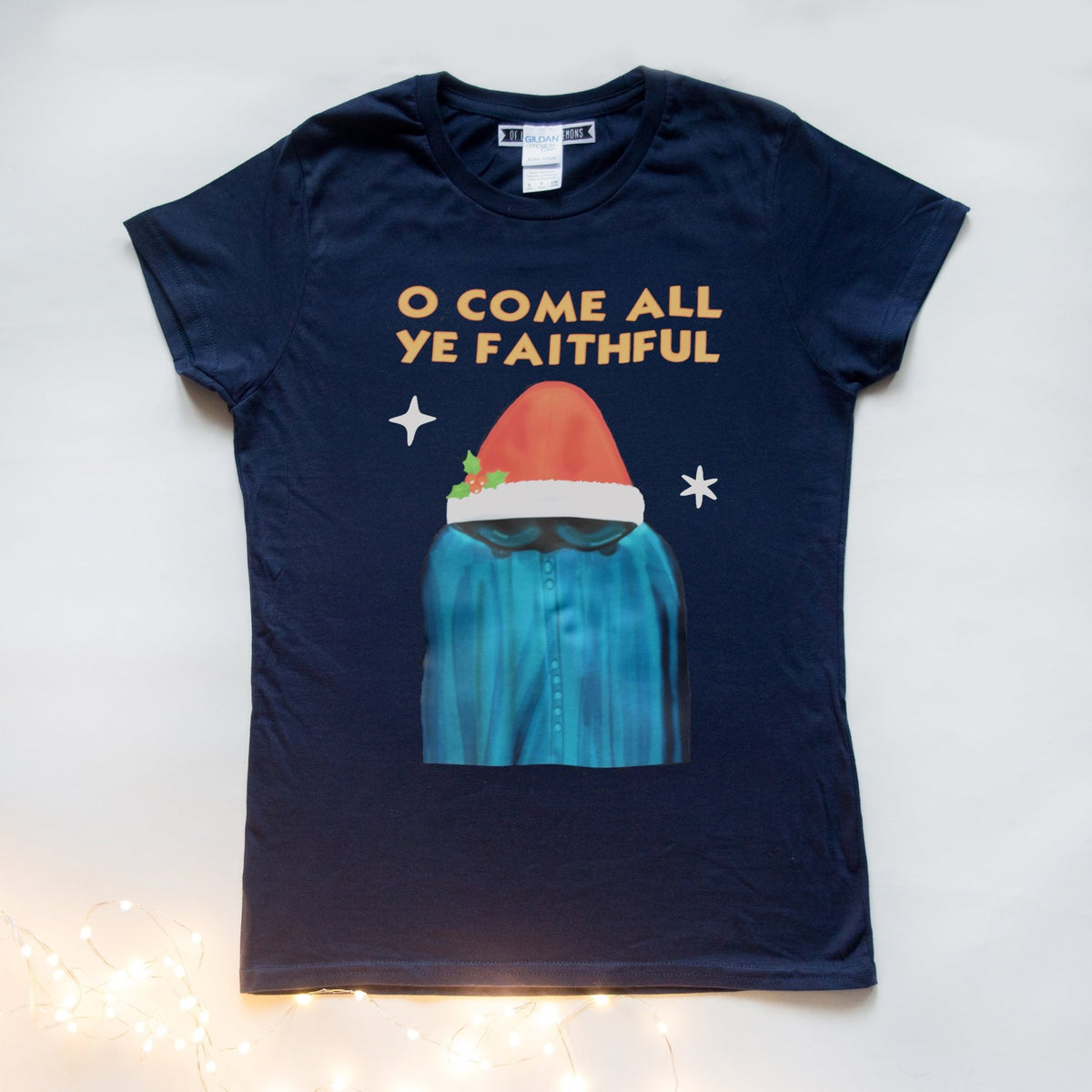 Navy blue t-shirt with a graphic of a Traitors TV show character in a blue robe and red Christmas hat, with 'O Come All Ye Faithful' text.