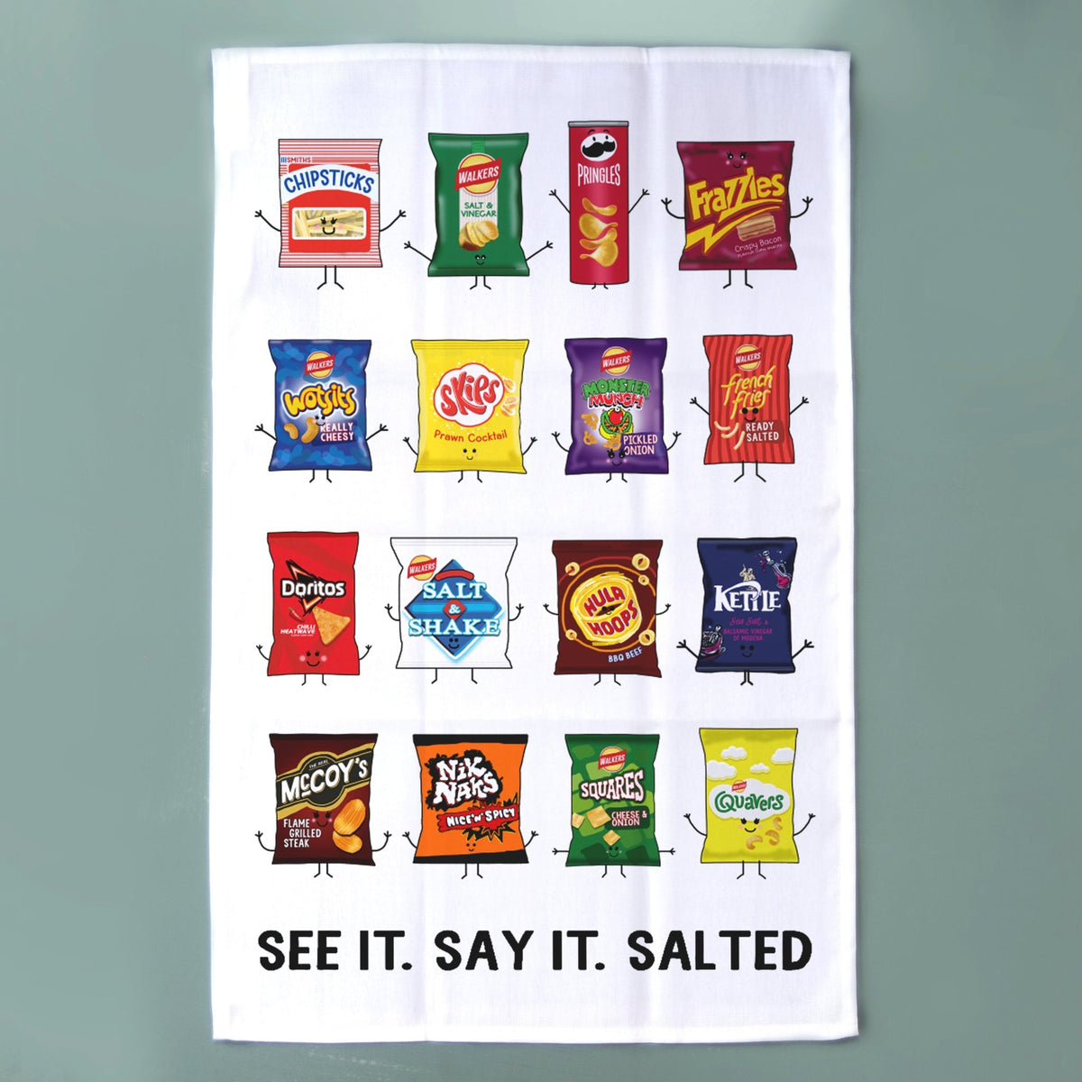 A white tea towel featuring a grid of cartoon-style snack bag illustrations with the text 'SEE IT. SAY IT. SALTED'
