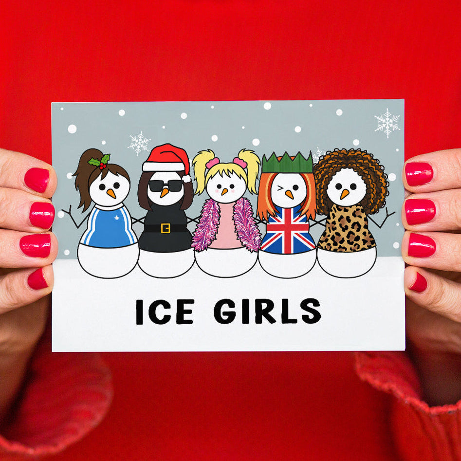 A person with red-painted nails holds a Christmas card featuring five cartoon snowmen dressed as The Spice GIrls in winter outfits, with the text 'ICE GIRLS' at the bottom. The person is wearing a bright red sweater against a red background.