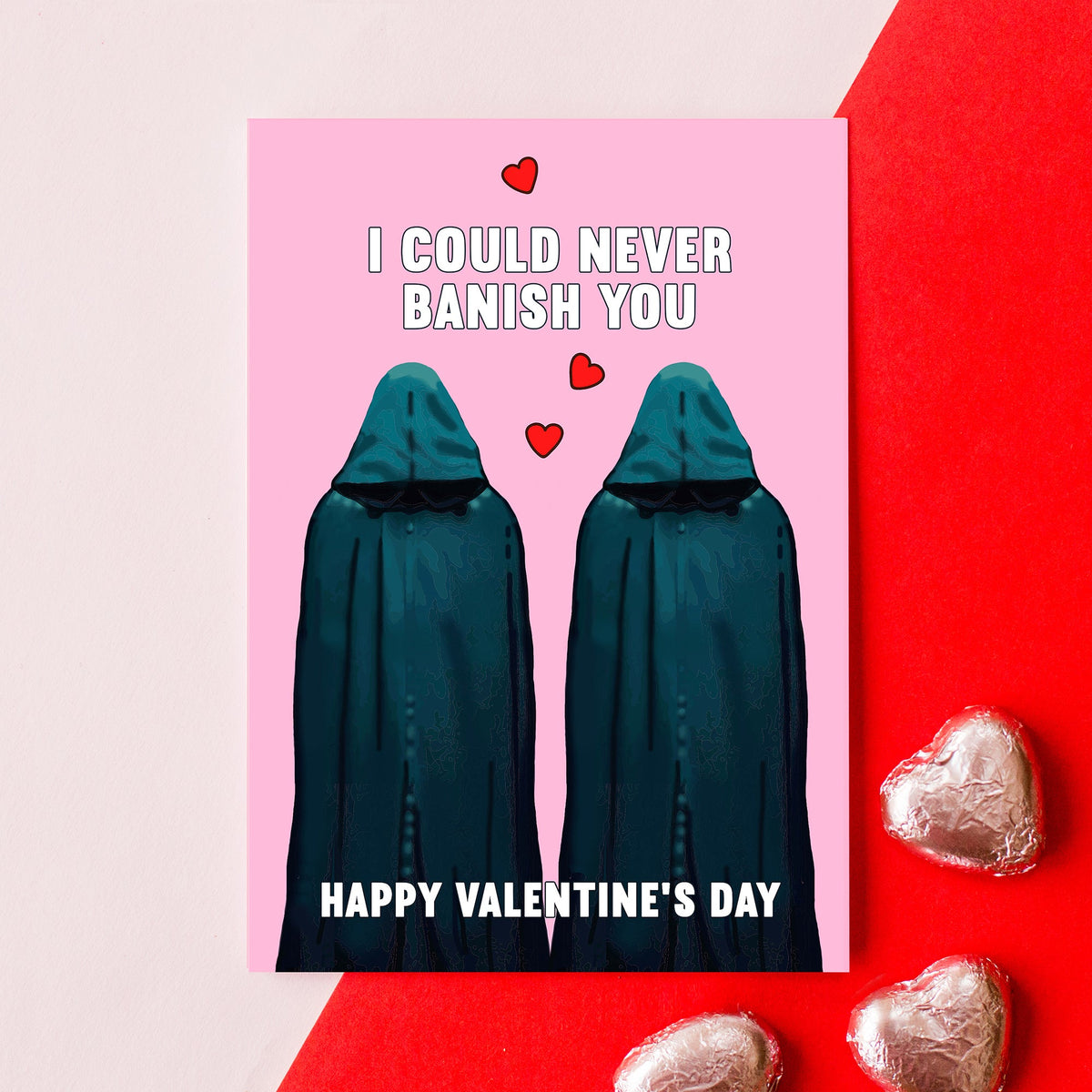 Valentine's Day card with two hooded Traitors figures and heart text on a pink and red background.