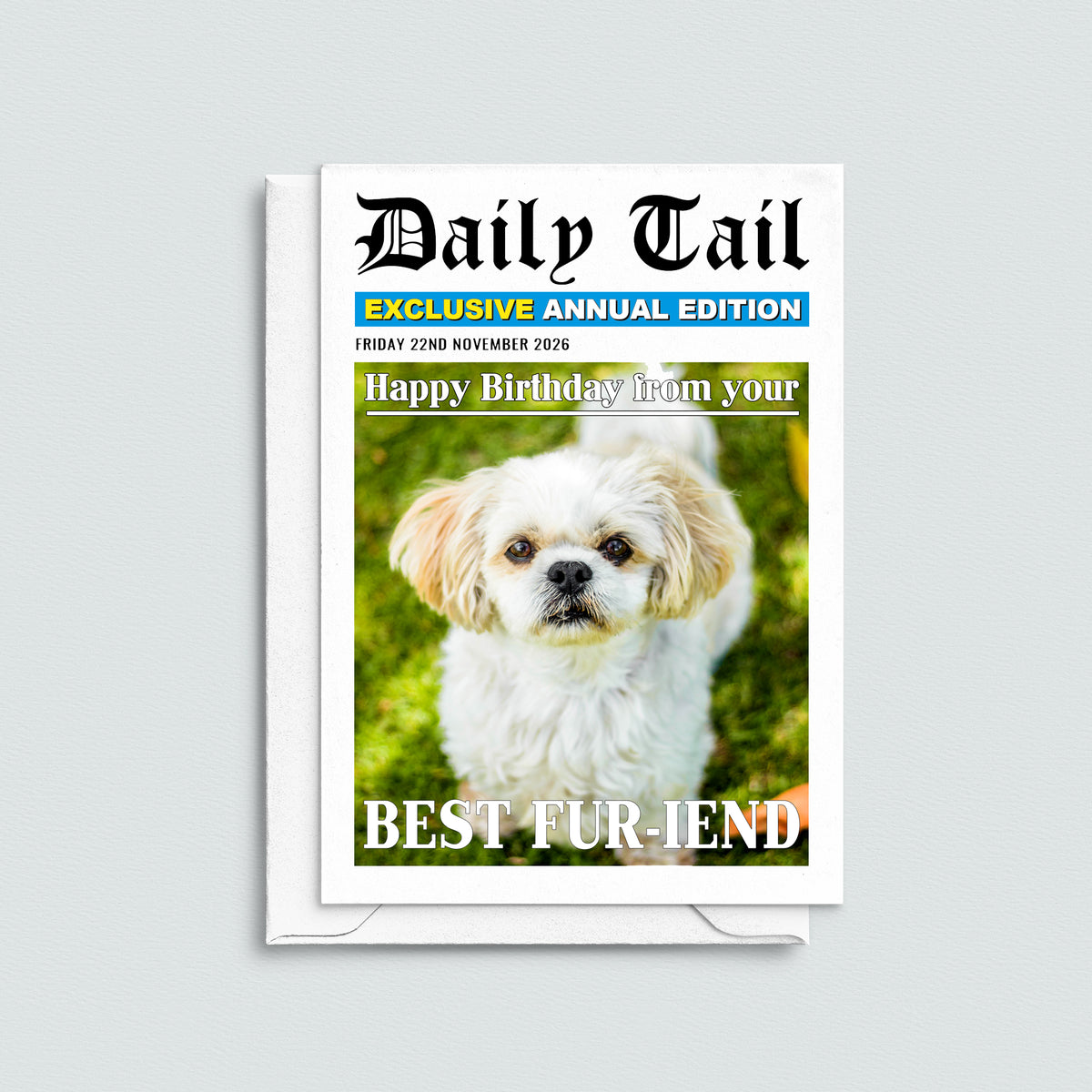 A novelty birthday card styled like a Daily Tail newspaper cover, featuring a photo of a small white dog on the front, shown standing upright on a white envelope against a light gray background.