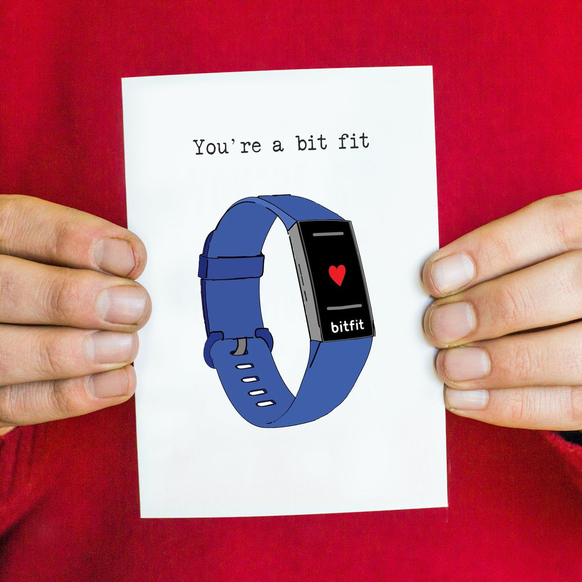 Card with a blue fitness tracker illustration and text 'You're a bit fit' held by hands against a red shirt.