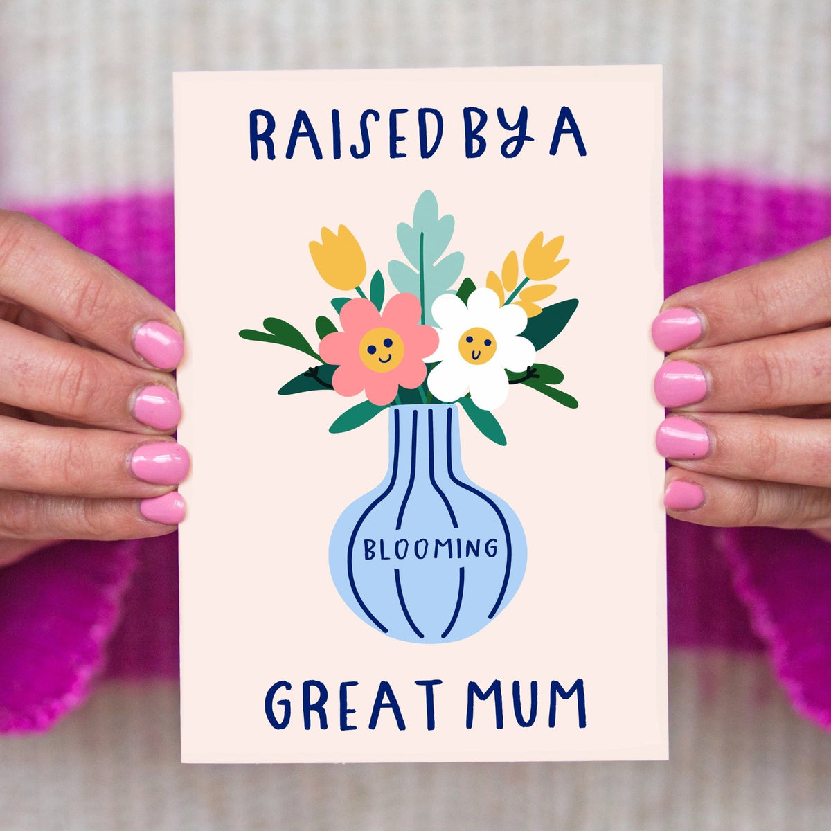 Mother's Day card with floral design and text 'Raised by a blooming great mum' held by hands.