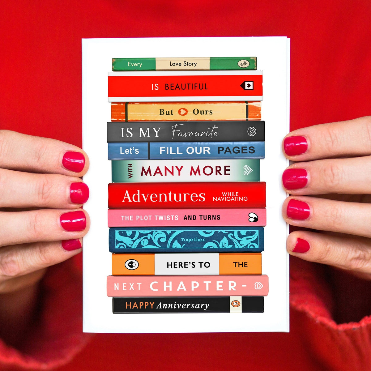 Stack of books with text on a card held by hands against a red background