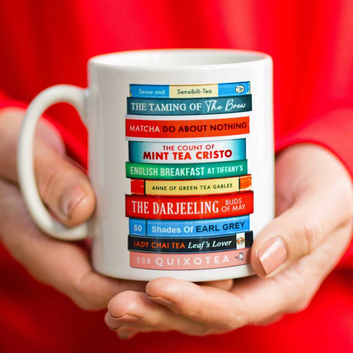 a ceramic mug with book stack illustration with book titles that are puns on classic book titles and tea 