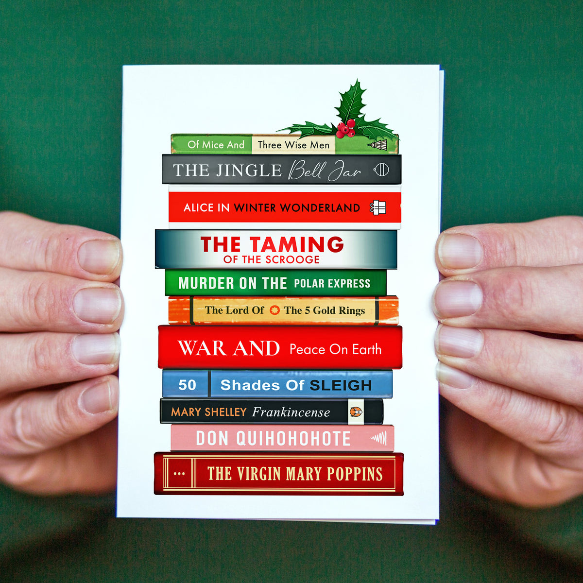 Christmas card with book stack design held by hands against a green background