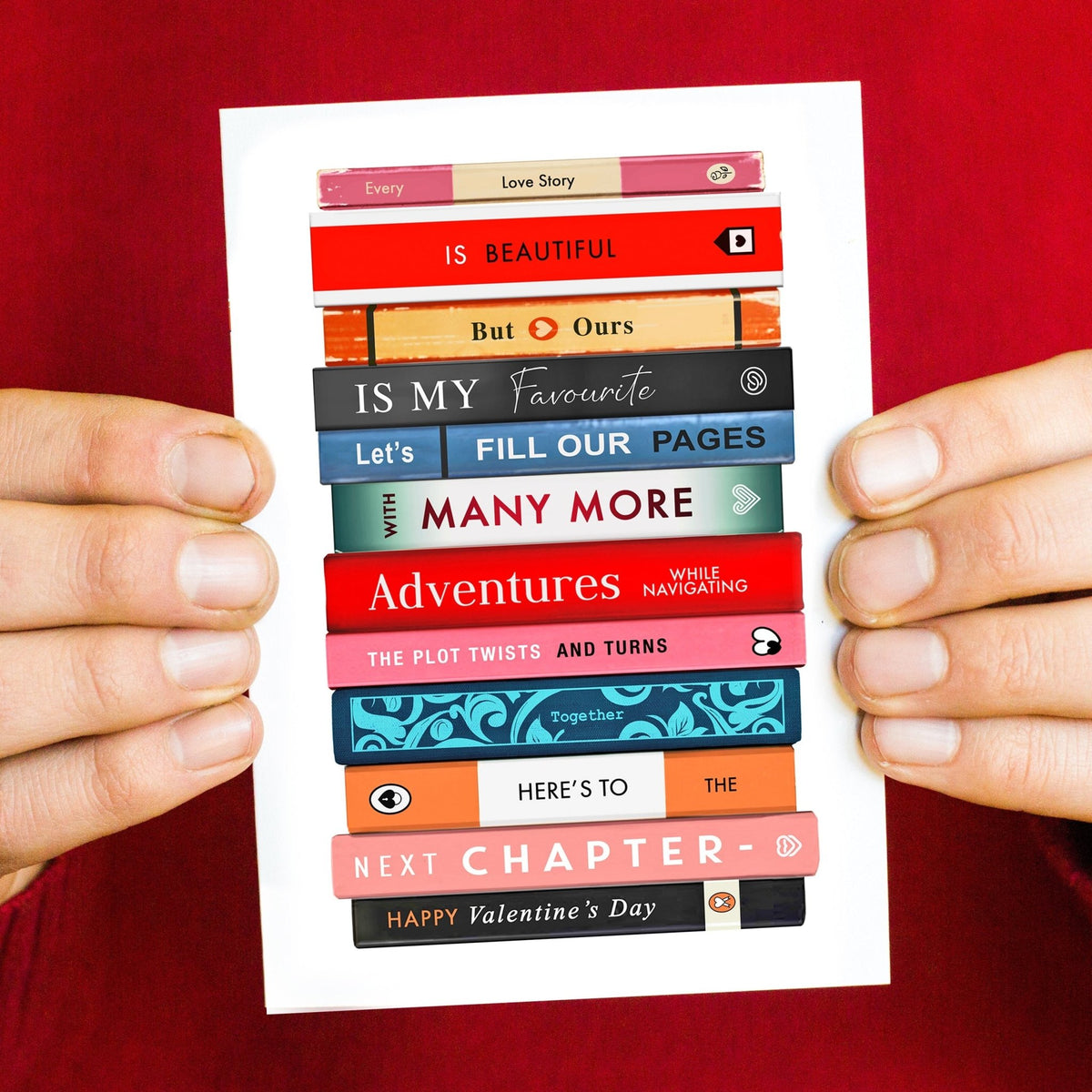 Valentine's Day card with a stack of books spelling out a romantic message design held by hands against a red background