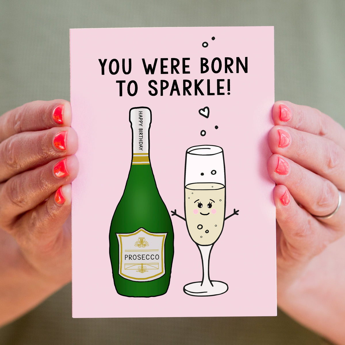 Card with Prosecco bottle and glass illustration and text 'You were born to sparkle' held by hands.