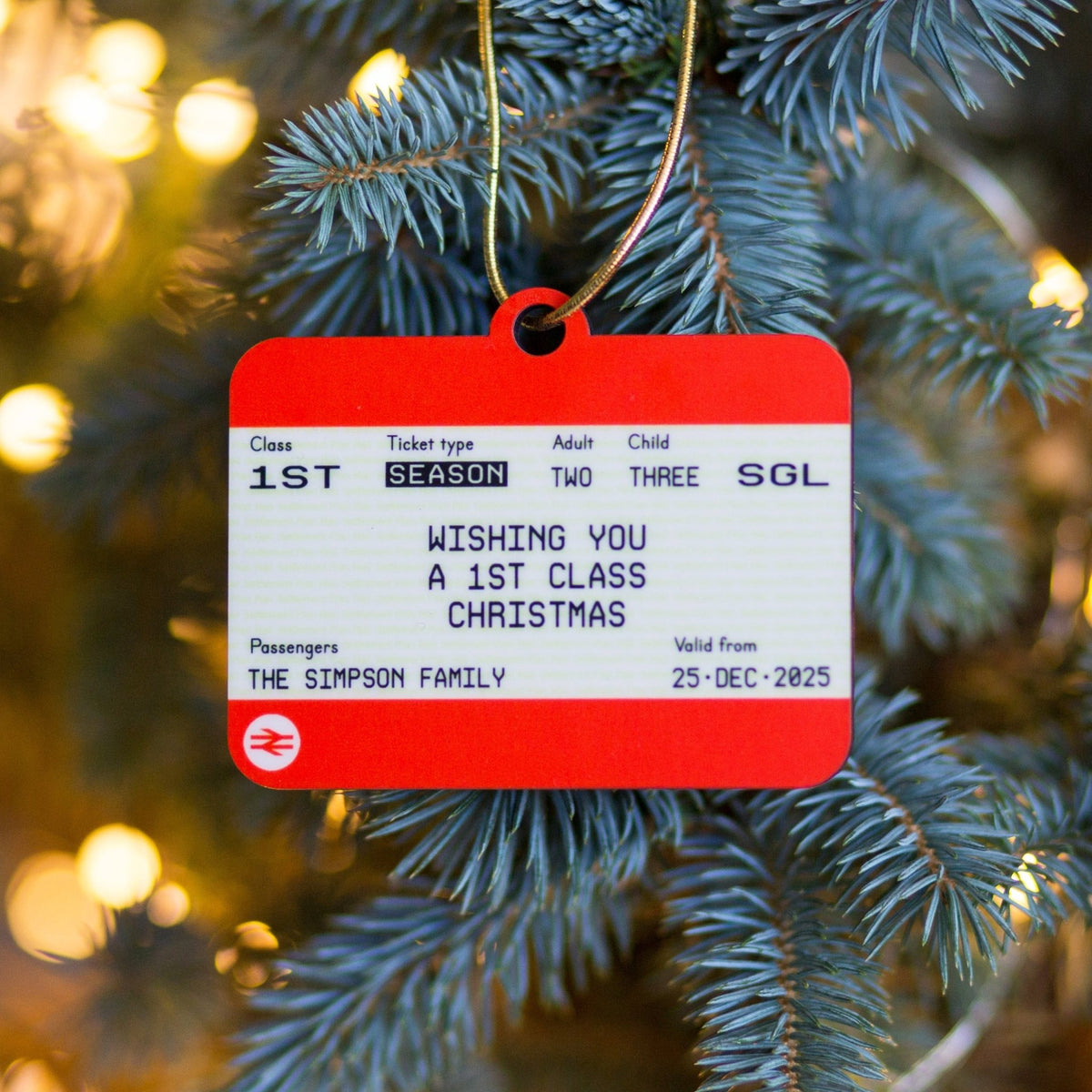 Red and white ticket ornament on a Christmas tree with festive lights in the background