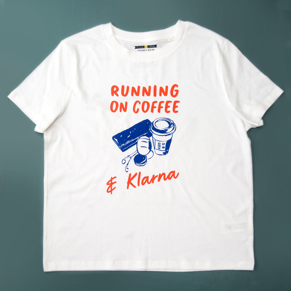 White t-shirt with 'Running on Coffee & Klarna' text and graphics on a dark green background