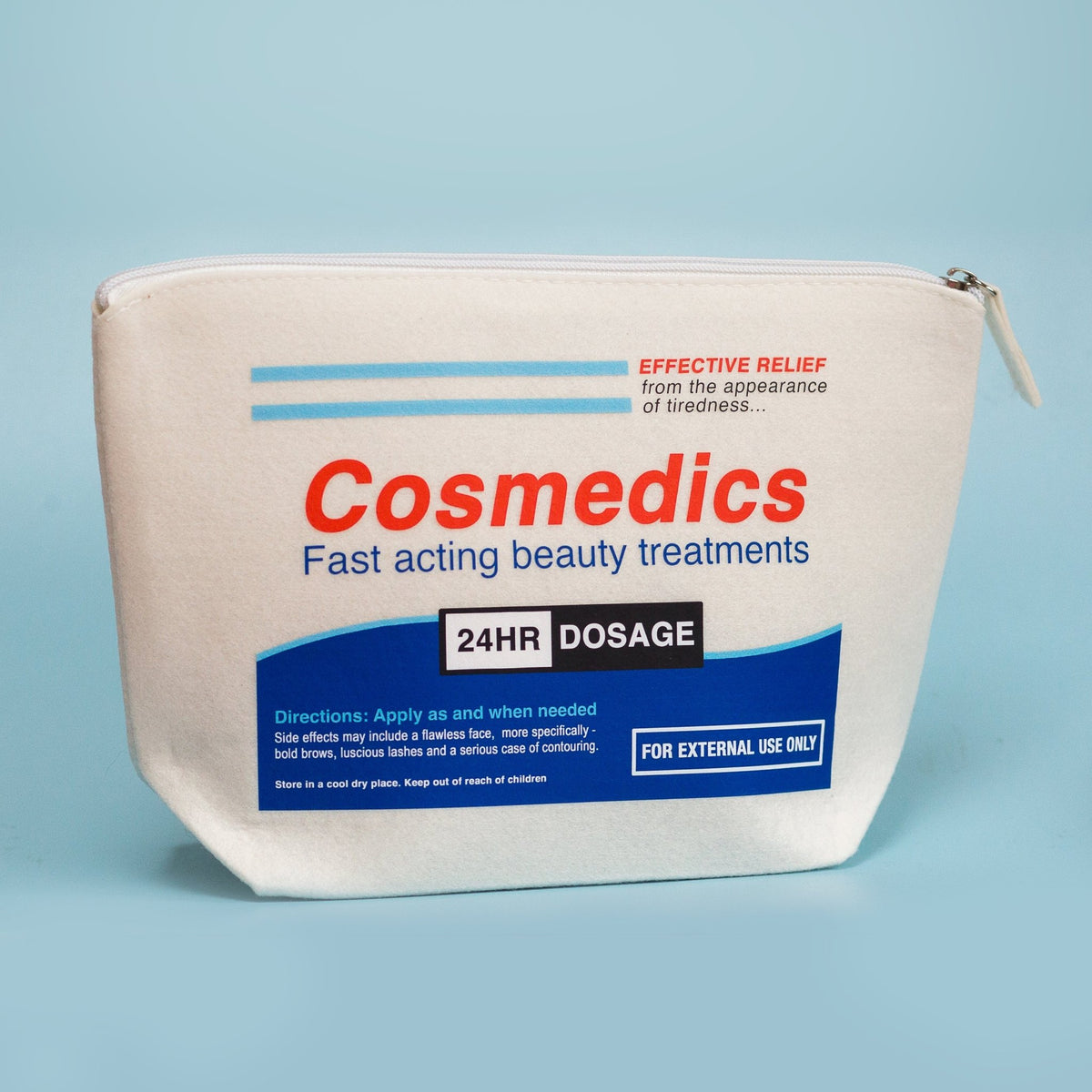 a make up bag that has a parody pill packet design called 'cosmedics' stood up on a blue background