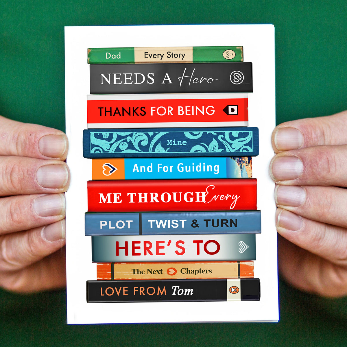 Father's Day card with book stack design held by hands against a green background