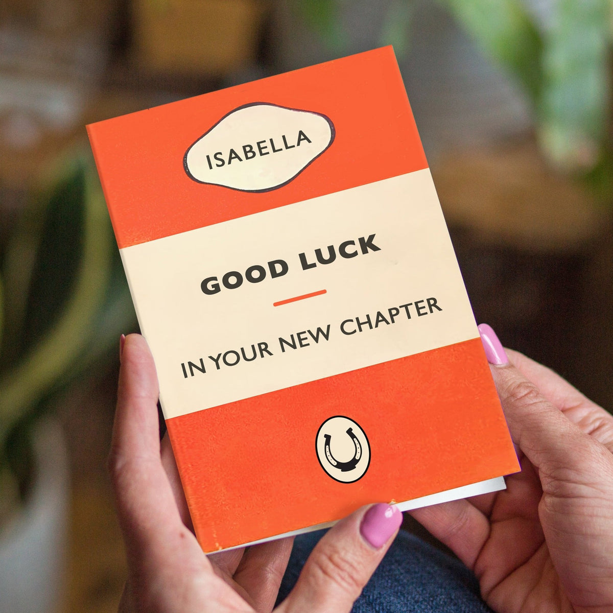 Person holding a small book with 'Good Luck in Your New Chapter' message