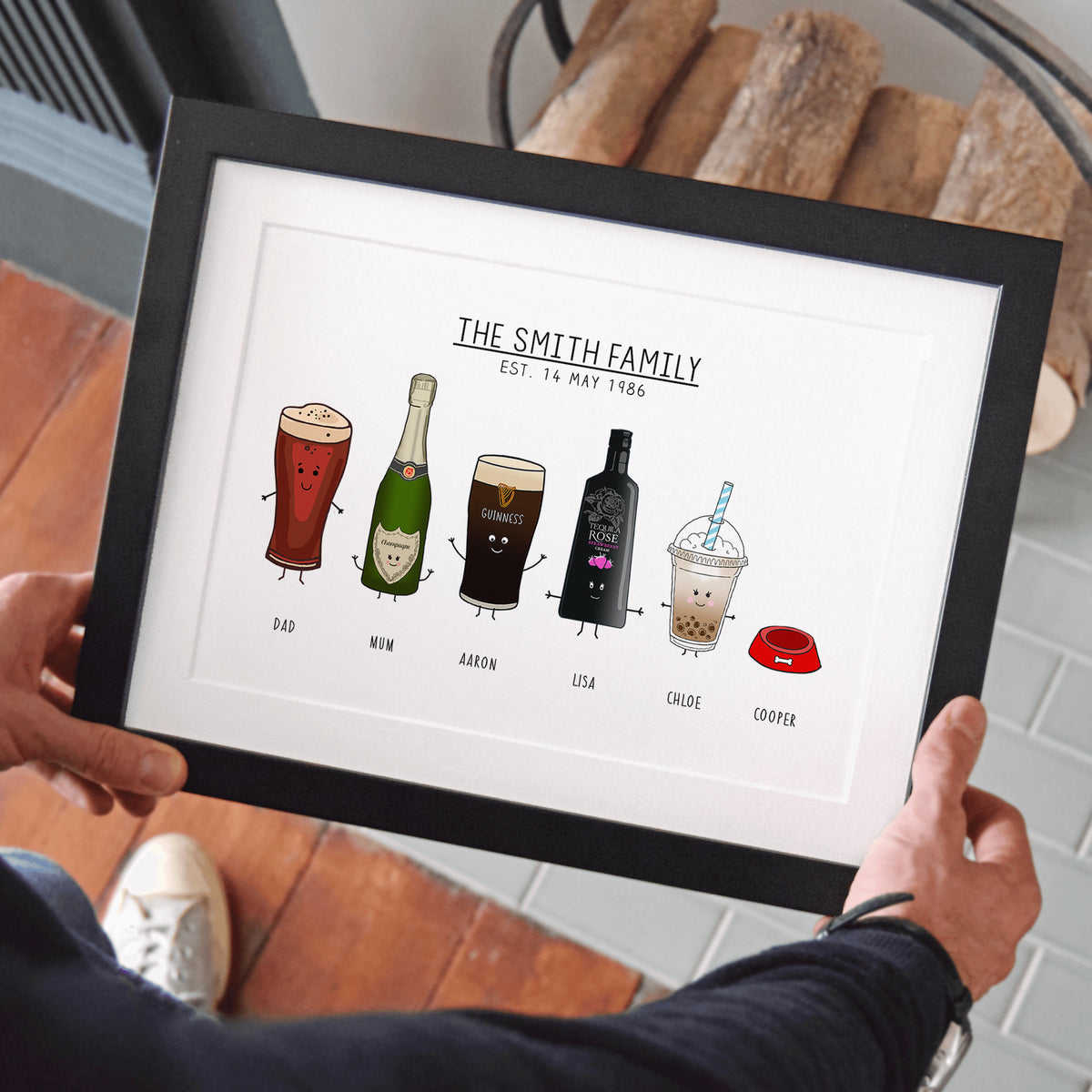 Framed artwork with illustrated drinks and 'The Smith Family' text, held by a person.