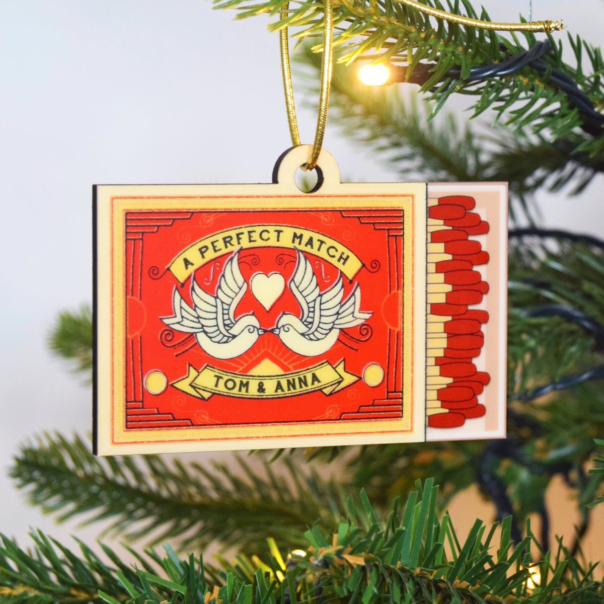 Matchbox ornament with 'A Perfect Match' design on a Christmas tree.