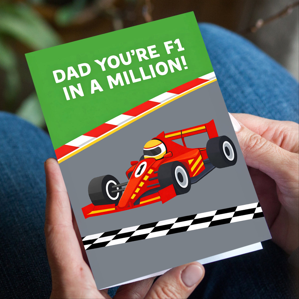 Greeting card with a racing car design and text held by hands.