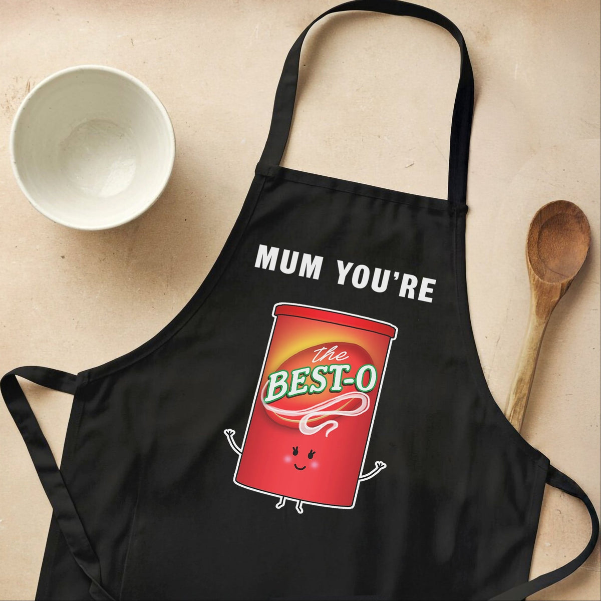 gravy themed apron for mum pictured on a cream background with a bowl and wooden spoon