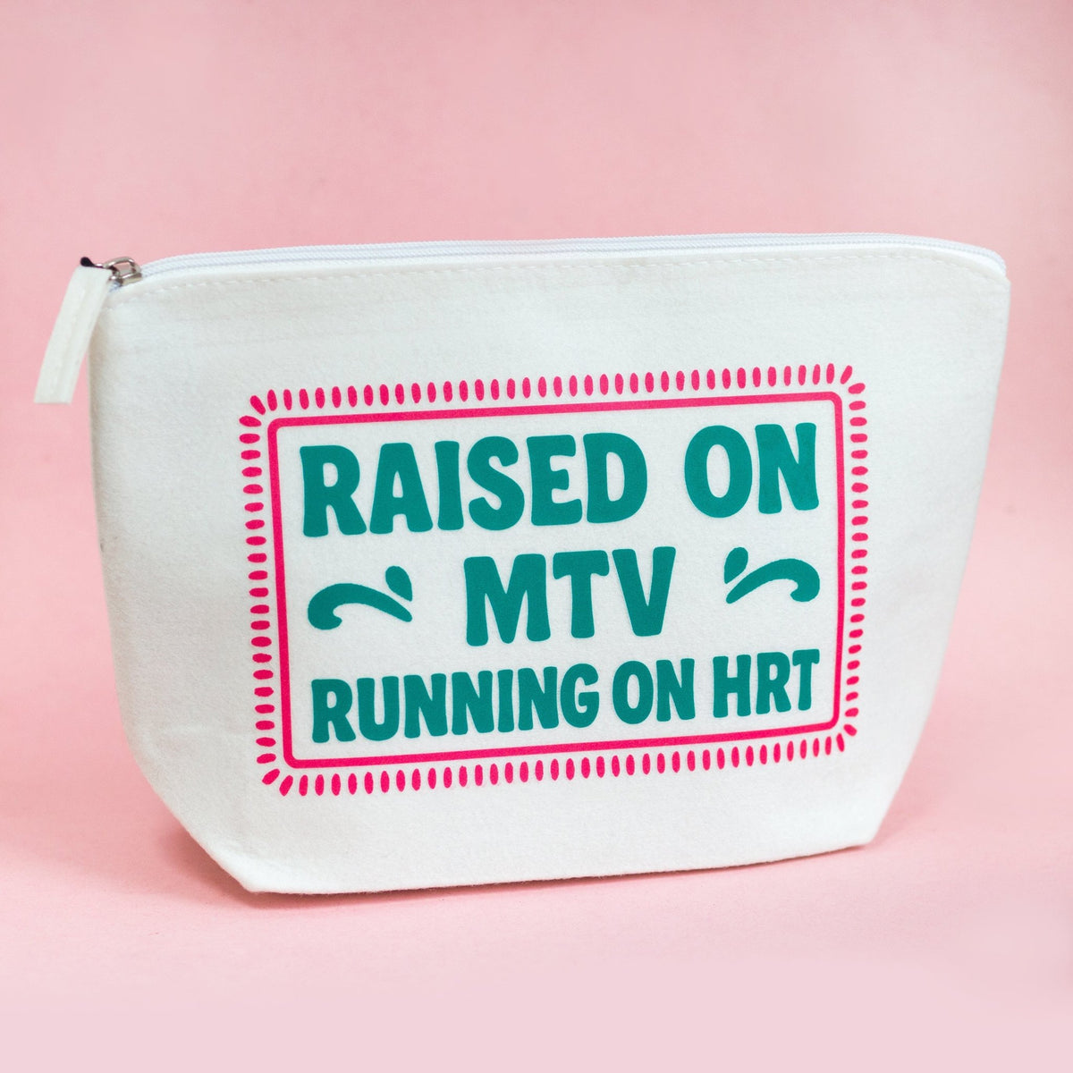 A white canvas zippered pouch with a pink and teal graphic that reads 'RAISED ON MTV RUNNING ON HRT' on a solid pink background.