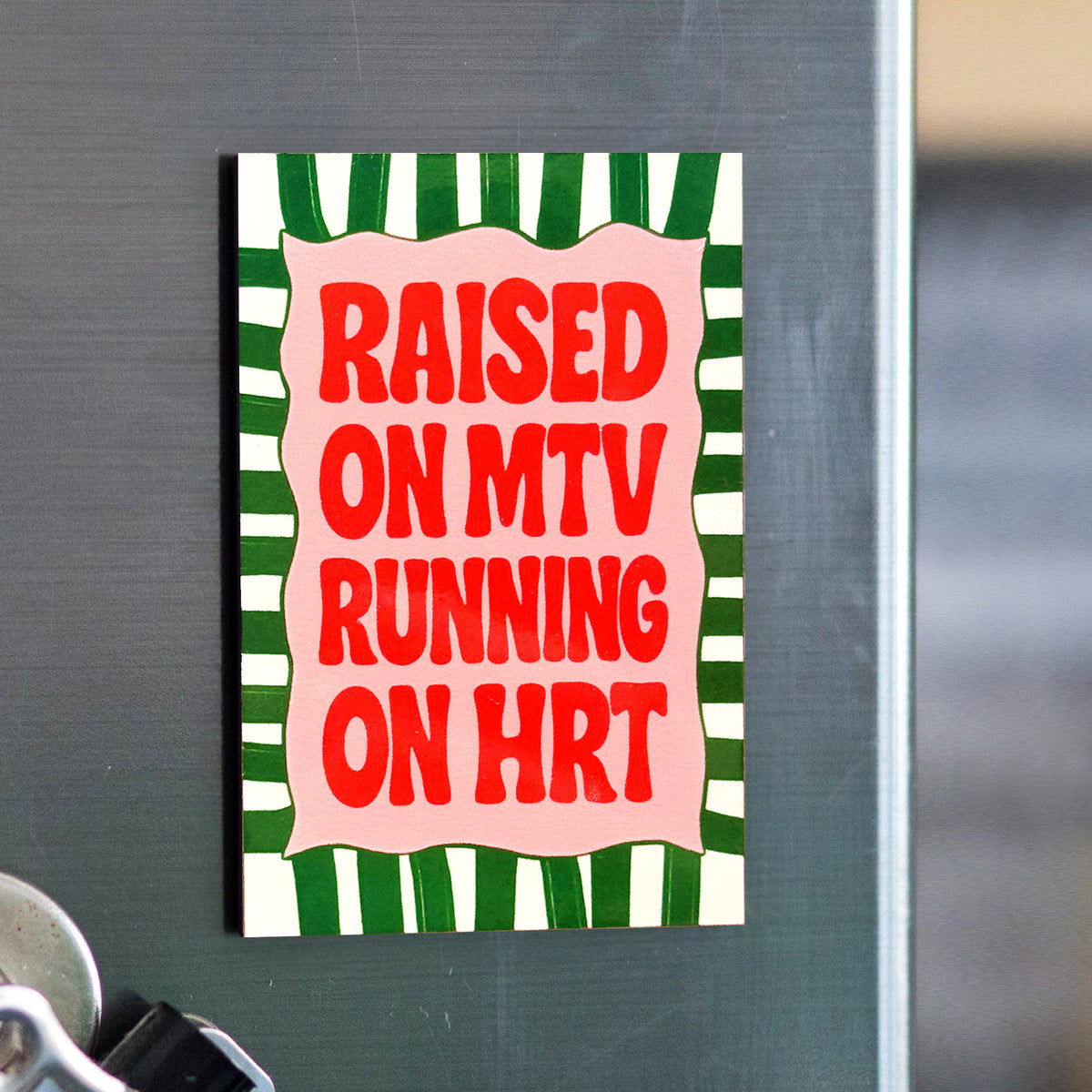Fridge magnet with red text 'Raised on MTV Running on HRT' on a green and white striped background.