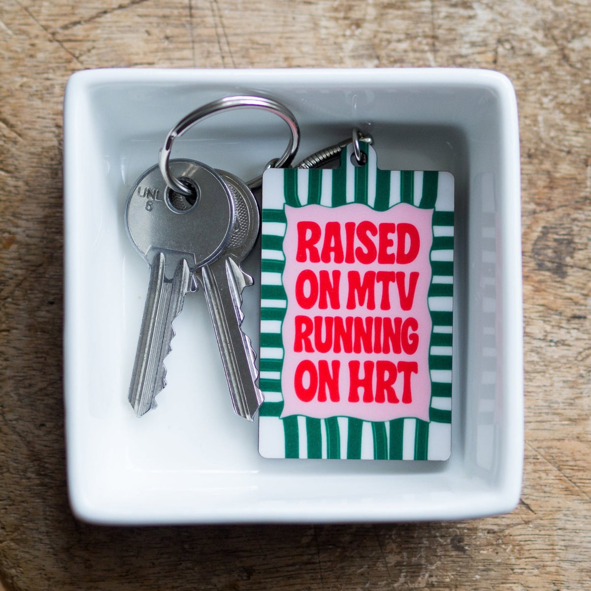 keyring that says raised on mtv running on hrt in a white dish with keys 