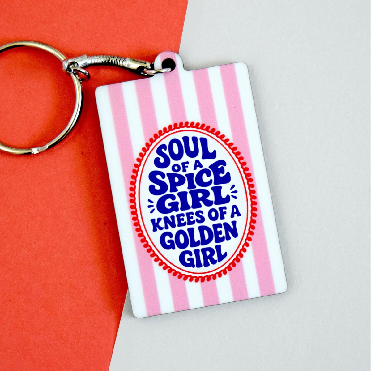 Keychain with 'Soul of a Spice Girl, Knees of a Golden Girl' text on a pink and white striped background