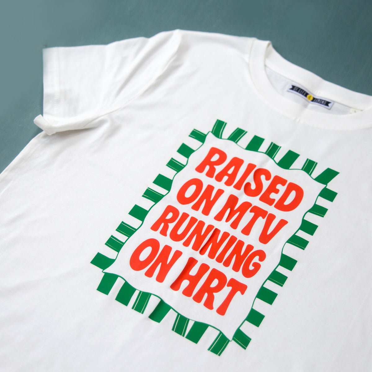 White t-shirt with red and green text design on a gray background