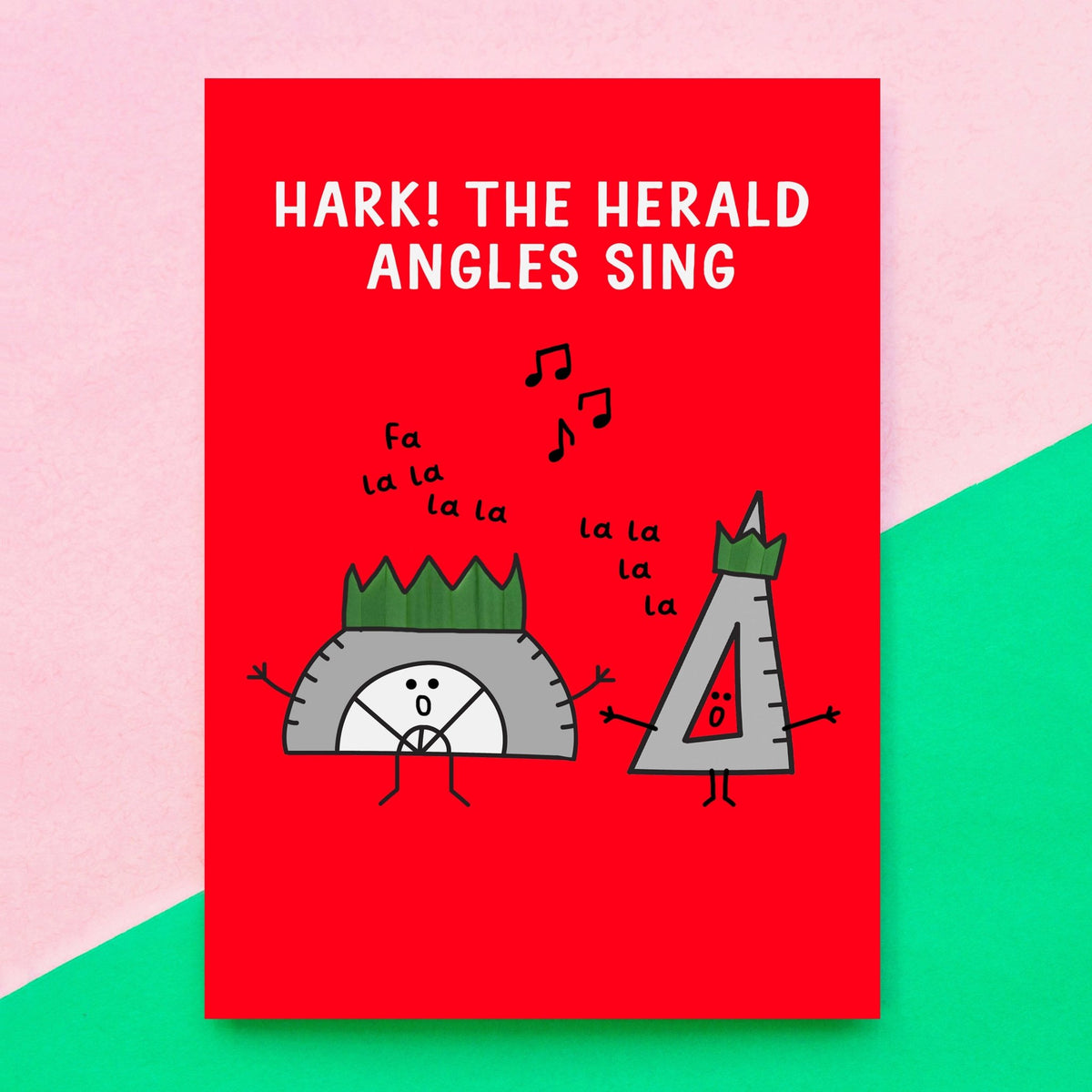A red christmas card featuring a cartoon illustration of a hedgehog and a triangle ruler singing, with the text 'HARK! THE HERALD ANGLES SING'. The card is displayed against a diagonally split pink and green background.
