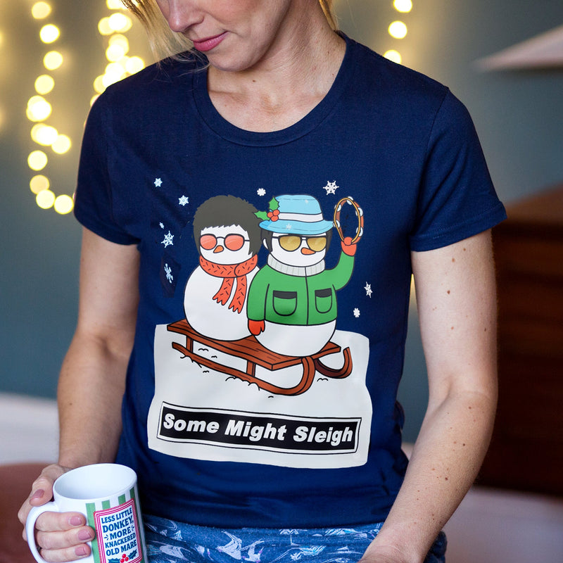 Person wearing a navy blue Christmas t-shirt with a snowman Liam and Noel Gallagher graphic and text, holding a mug.