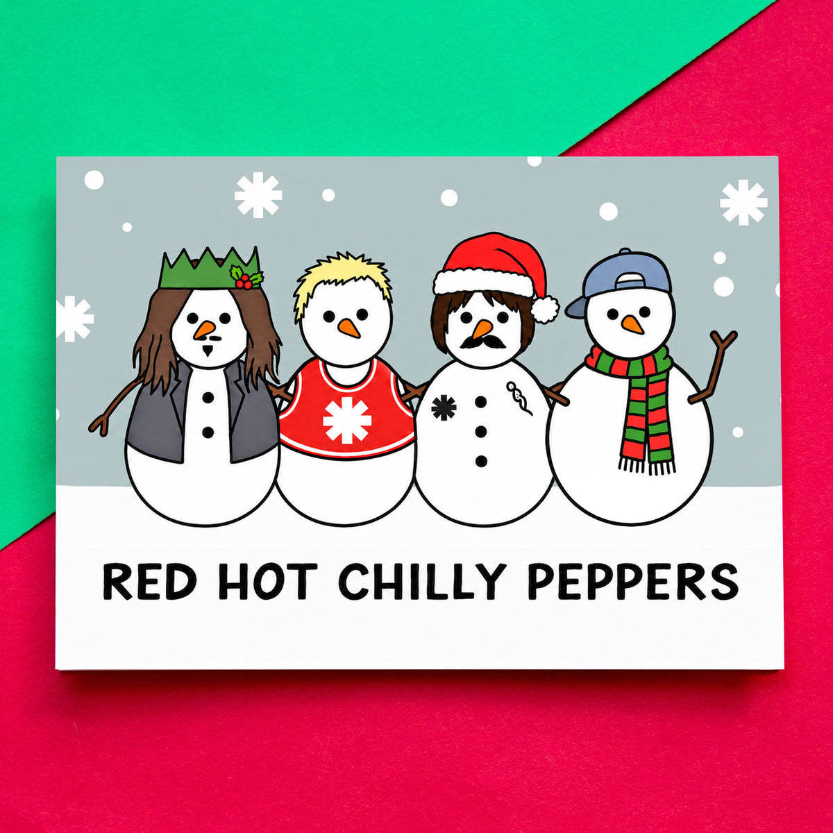 A Christmas card featuring four cartoon snowmen with winter clothing and the text 'RED HOT CHILLY PEPPERS' at the bottom, placed on a bright pink and green background.
