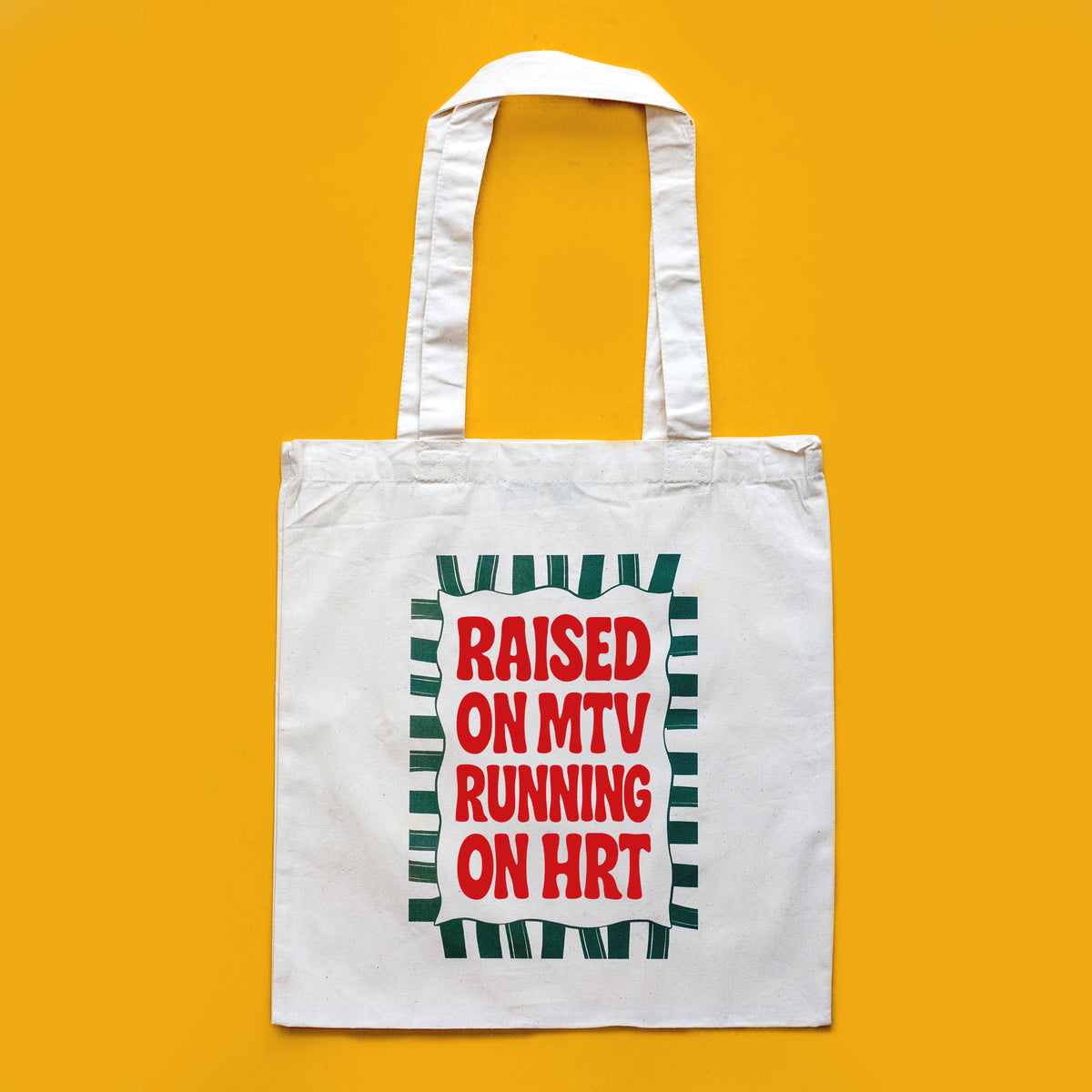 A white canvas tote bag with two shoulder straps, featuring a graphic print on the front with the text 'RAISED ON MTV RUNNING ON HRT' in red letters inside a green-and-white striped border, set against a solid yellow background.