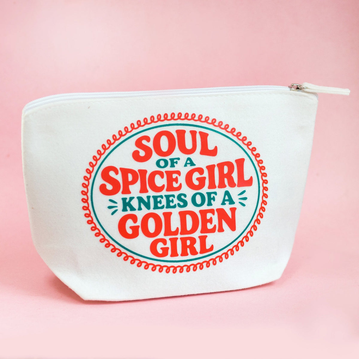 A white canvas zippered pouch featuring a retro circular graphic that reads 'SOUL OF A SPICE GIRL KNEES OF A GOLDEN GIRL' in red and teal lettering, set against a solid pink background.