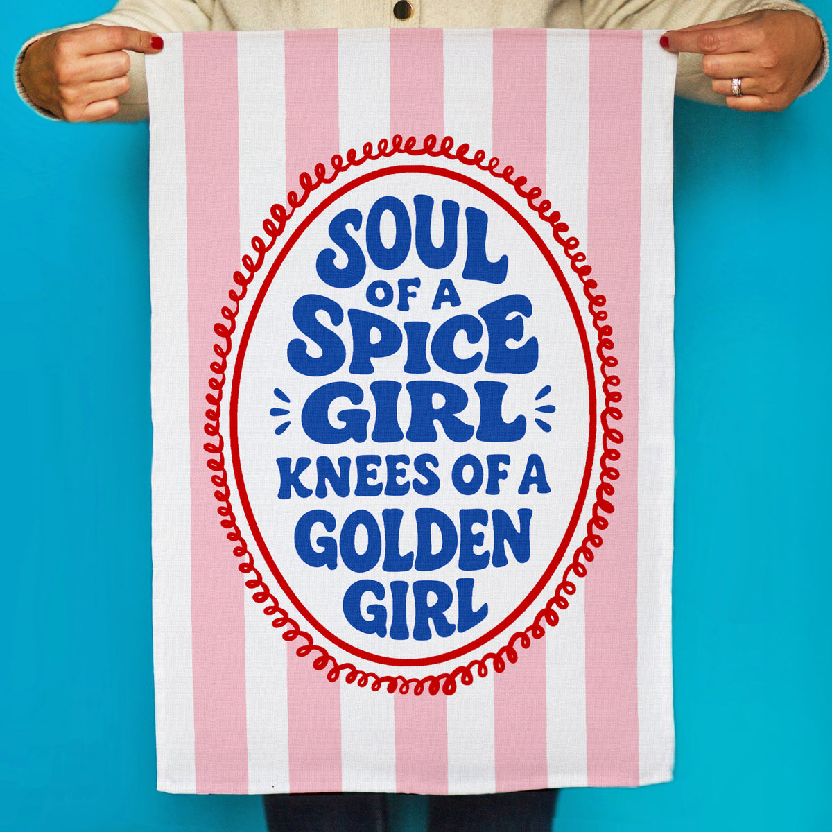 Striped towel with text 'Soul of a Spice Girl, Knees of a Golden Girl' held by a person against a blue background