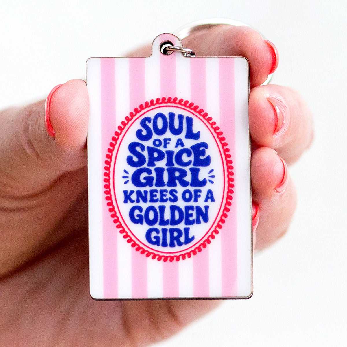 keyring with soul of a spice girl knees of a golden girl slogan held in female hand
