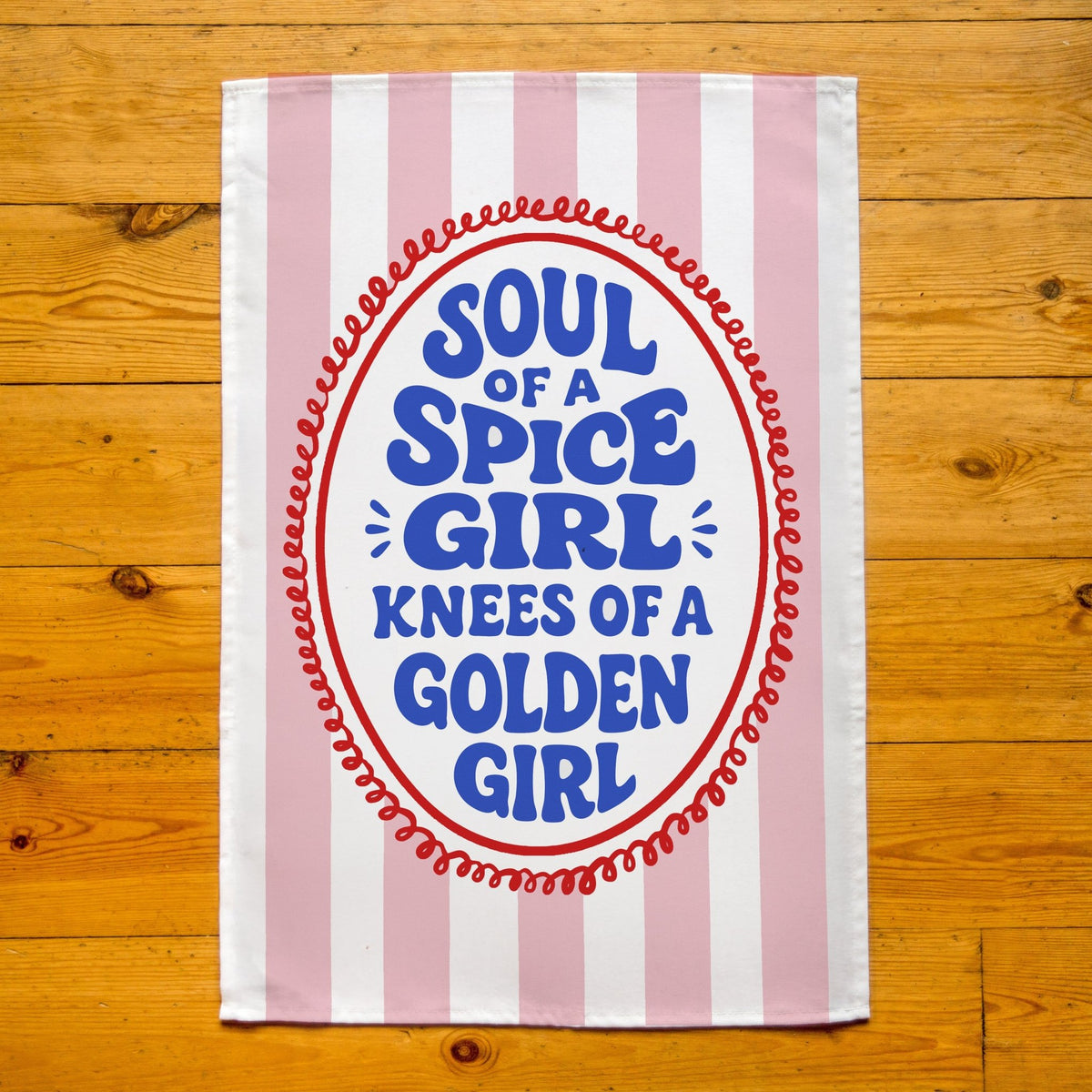 Striped towel with text 'Soul of a Spice Girl, Knees of a Golden Girl' on a wooden surface