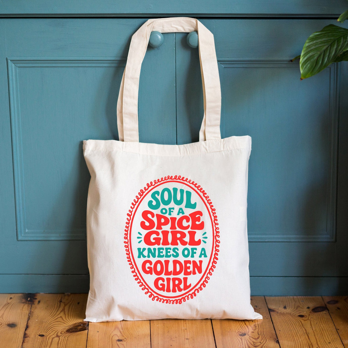 a funny tote bag with the slogan soul of a spice girl knees of a golden girl against a blue wooden cupboard and wooden floor
