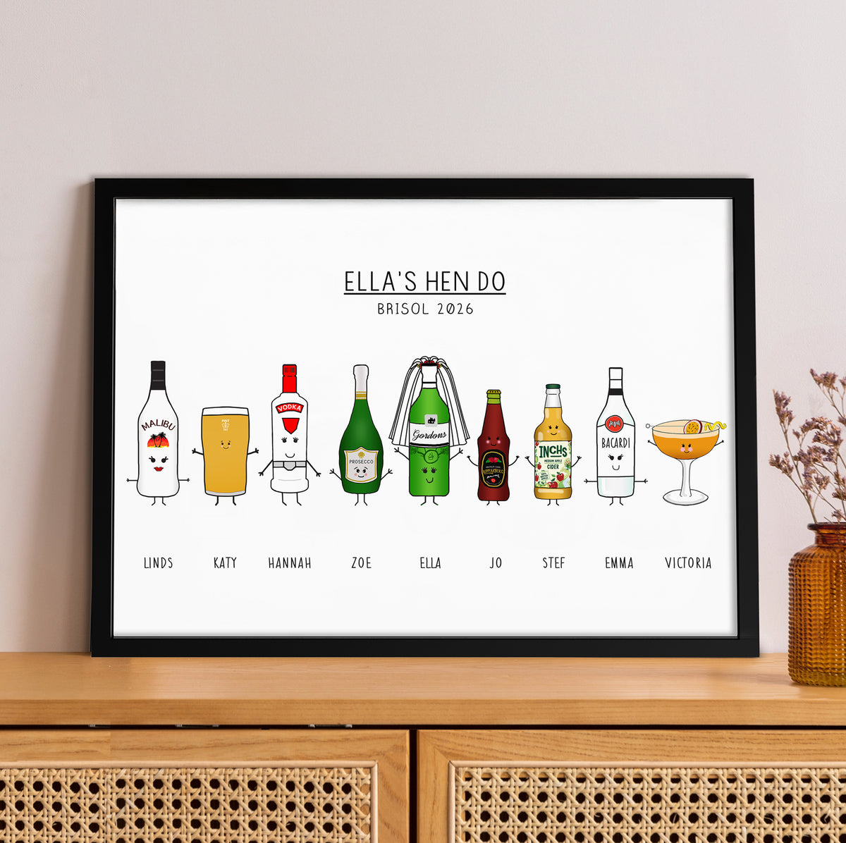 Framed artwork with cartoon drinks characters and text on a wall above a wooden cabinet.