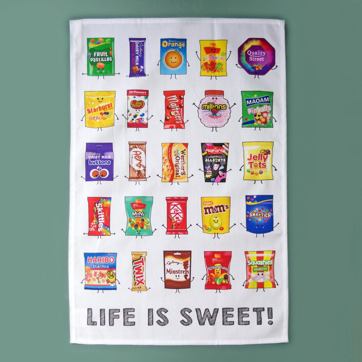 illustrated sweets tea towel laid out on a green background