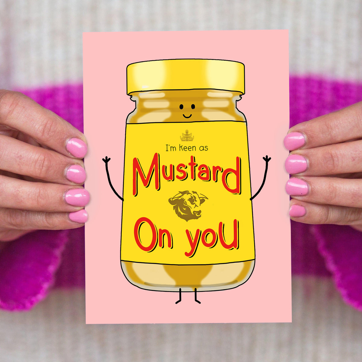 Cartoon mustard jar with text held by hands against a pink background