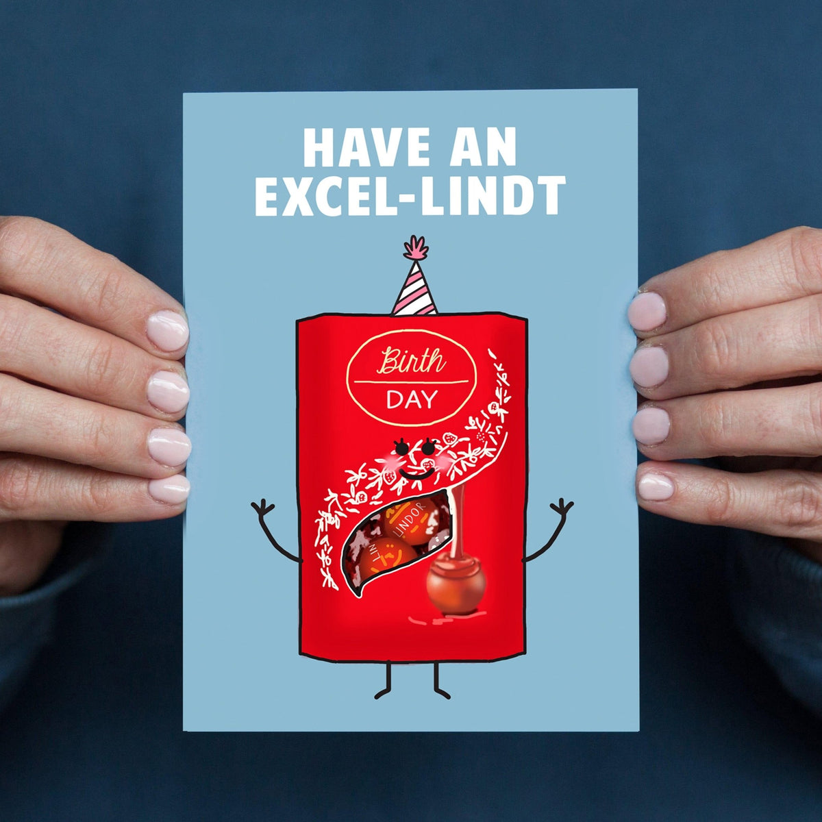 Card with a red Lindt chocolate bar character and text 'Have an Excel-lindt Birthday' held by hands against a blue background.