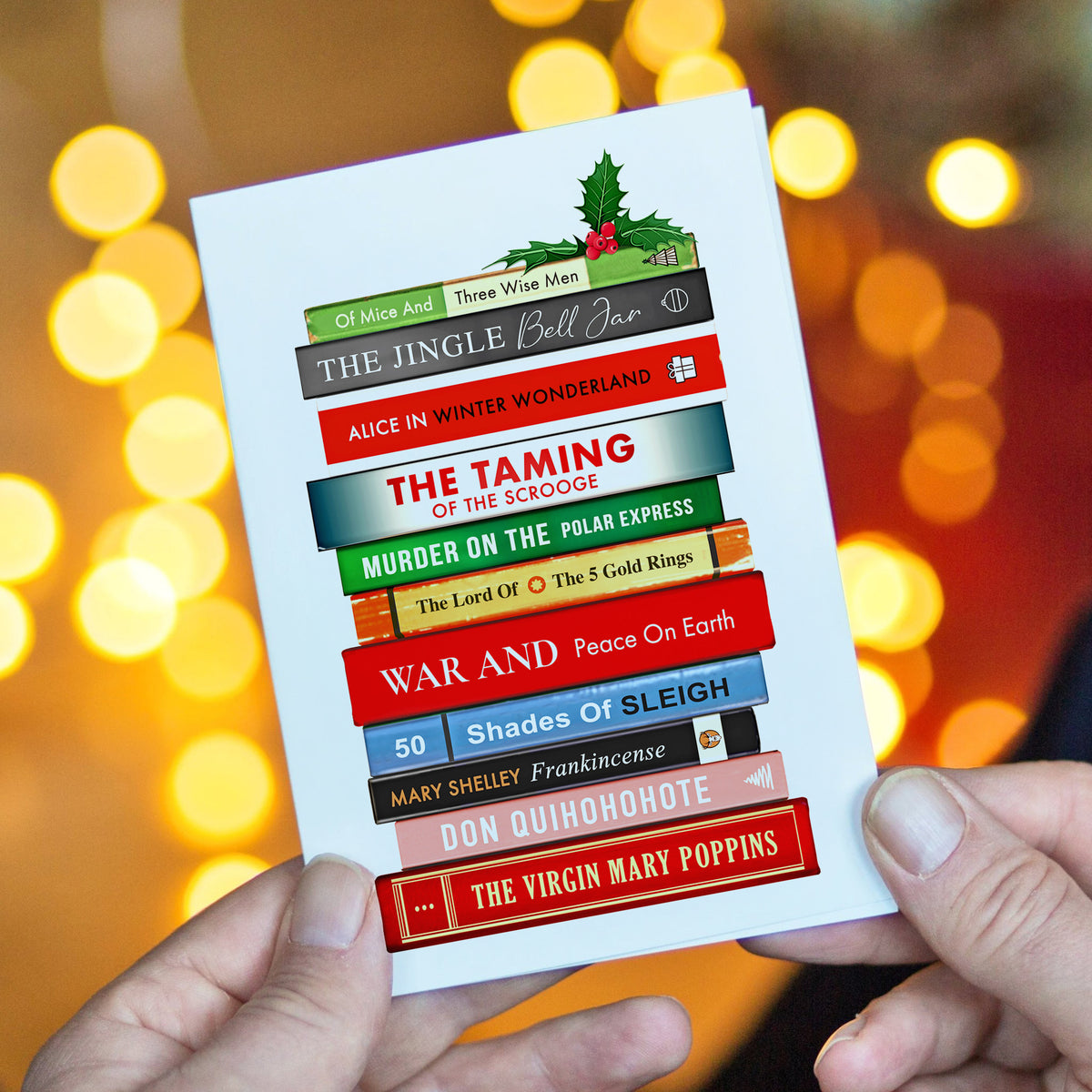 Christmas card with book titles arranged like books, held against a blurred festive background.