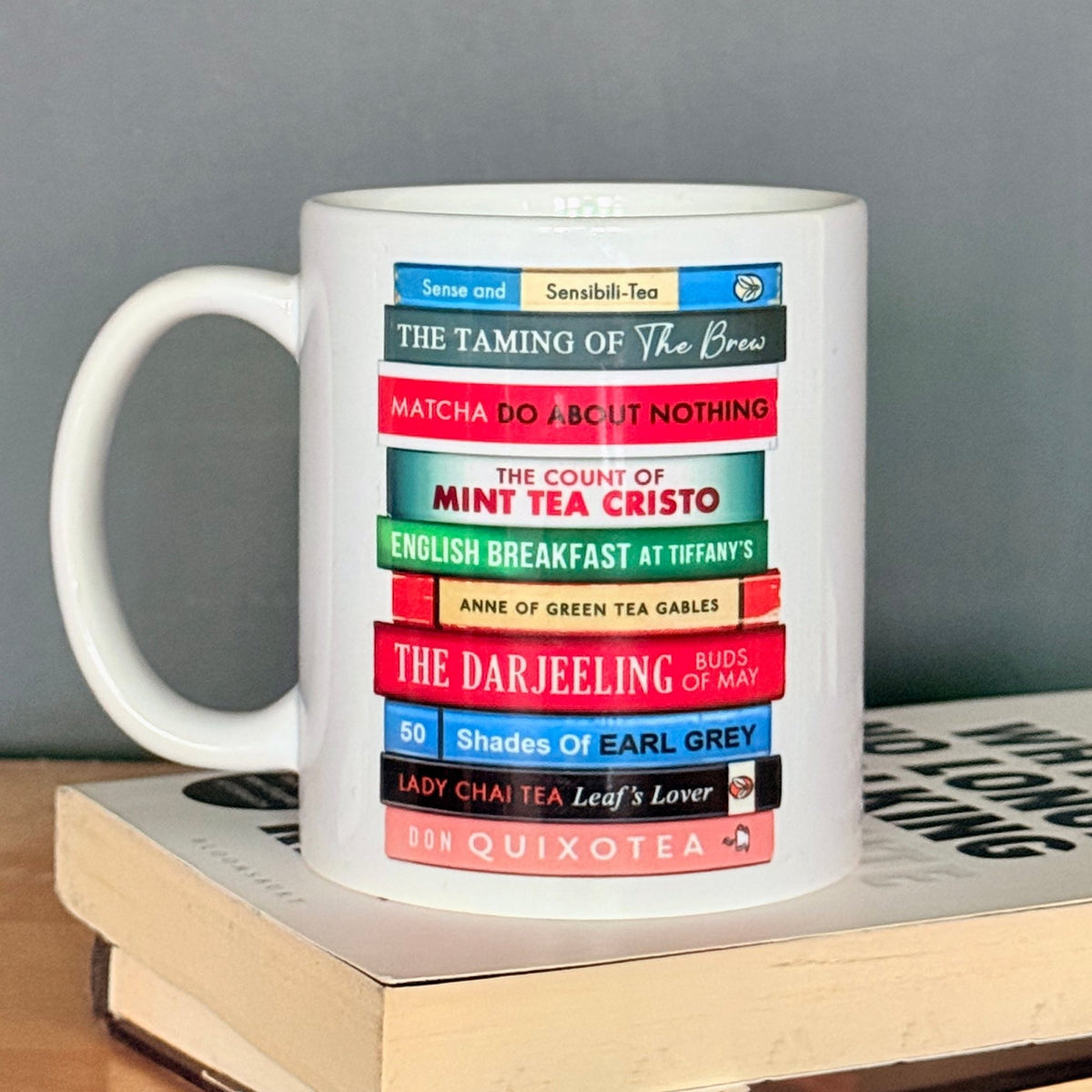 White mug with colorful book stack design on a gray background