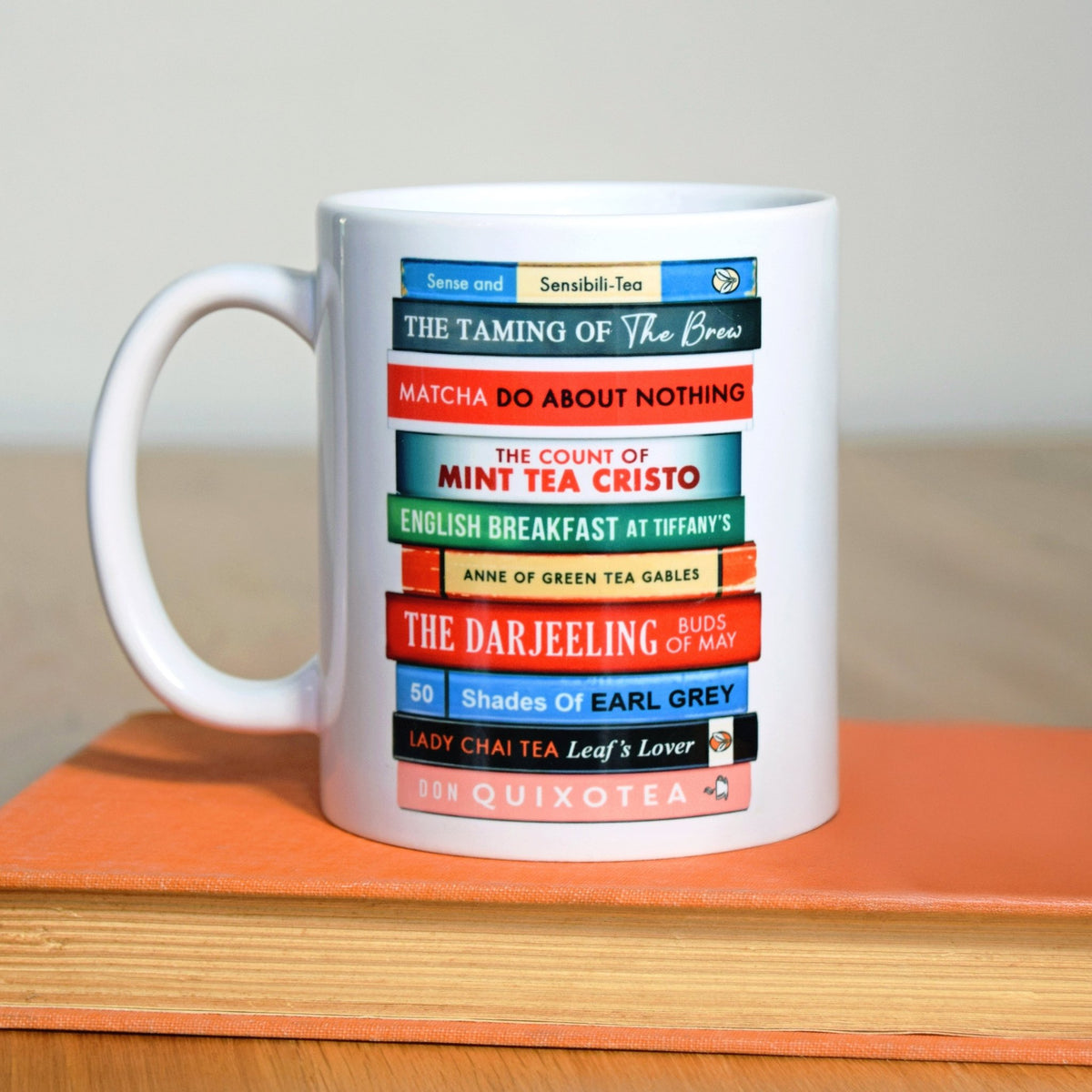 White mug with colorful book title puns design on a wooden surface