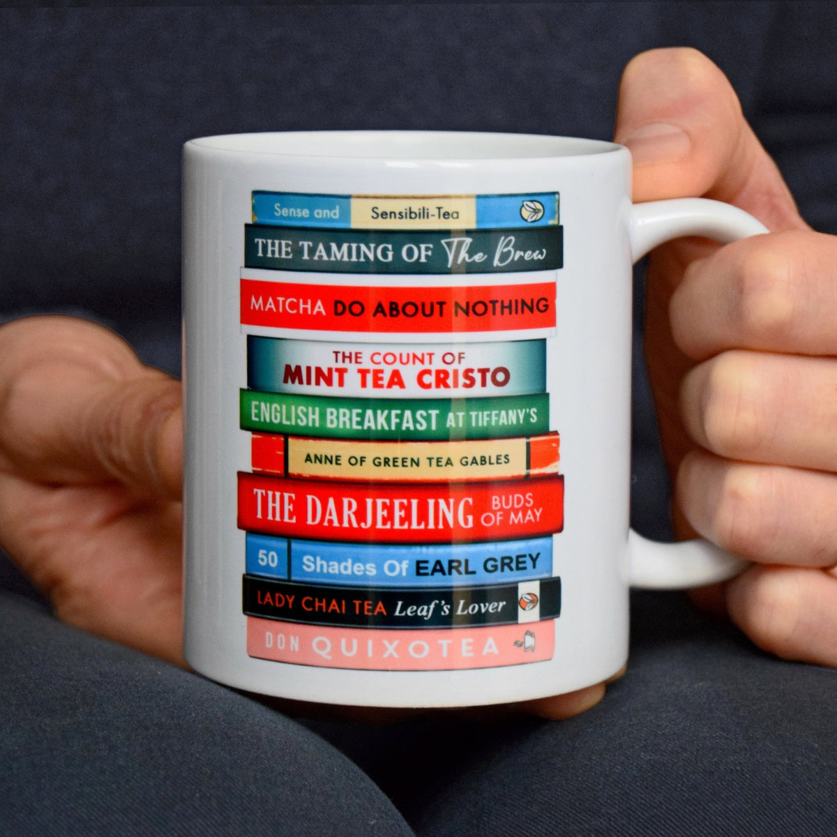 White mug with colourful book design held by a person