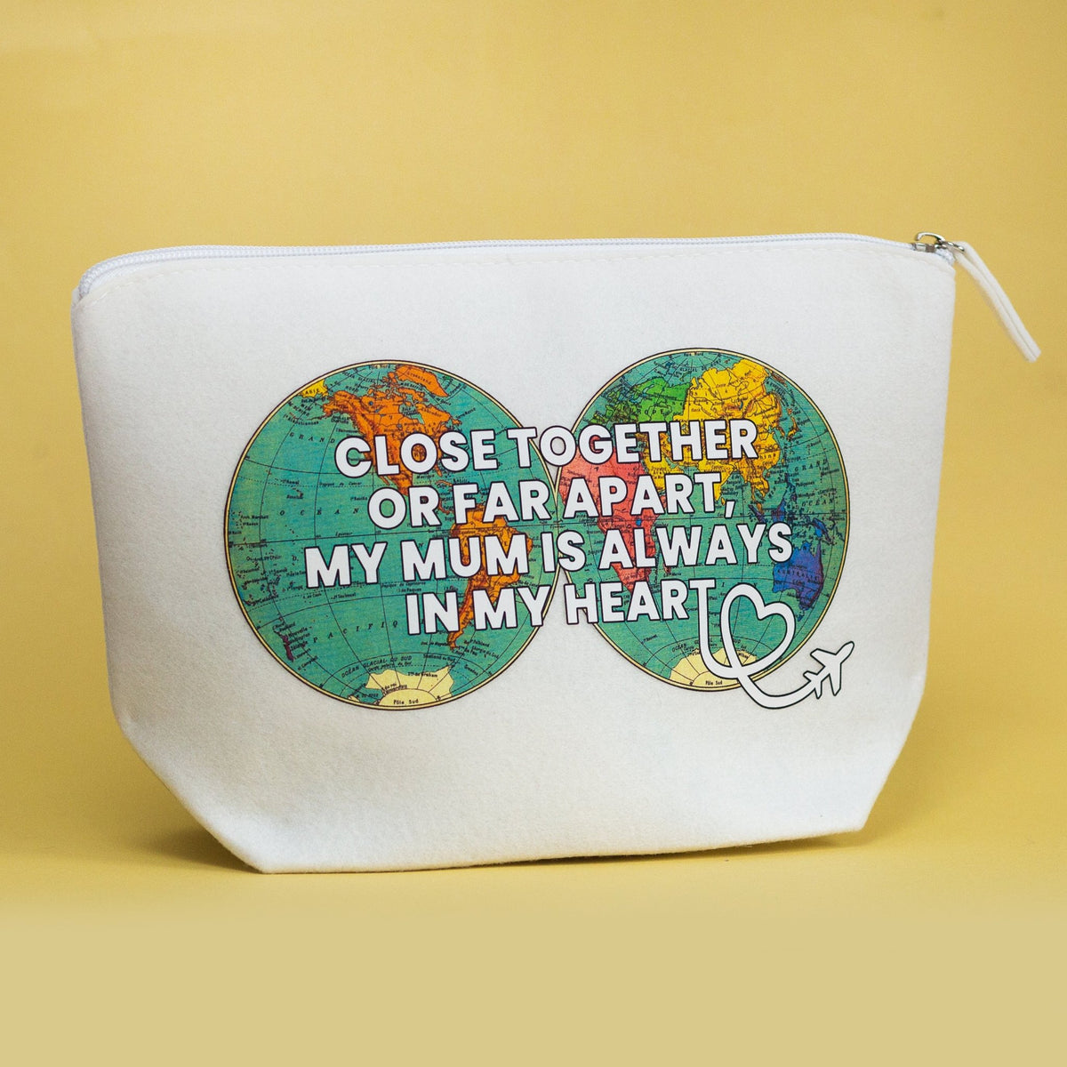 A white canvas zippered pouch with a printed graphic of two map circles connected by an infinity symbol, featuring the text 'CLOSE TOGETHER OR FAR APART, MY MUM IS ALWAYS IN MY HEART' in white letters, set against a solid yellow background.