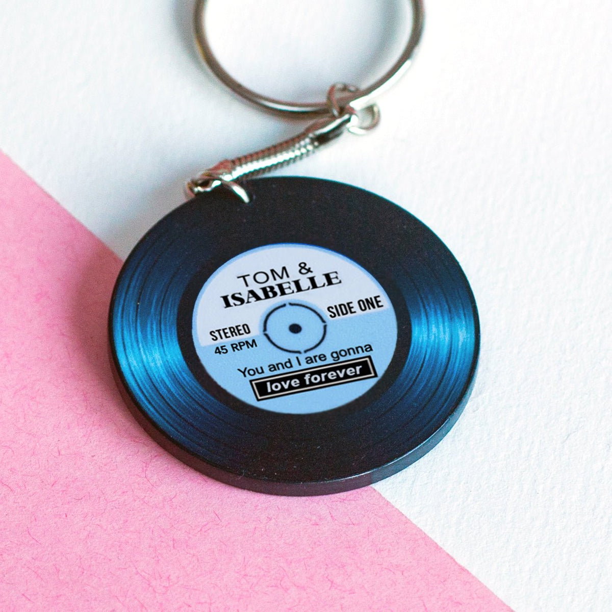 Vinyl record keychain with personalized text on a pink and white background
