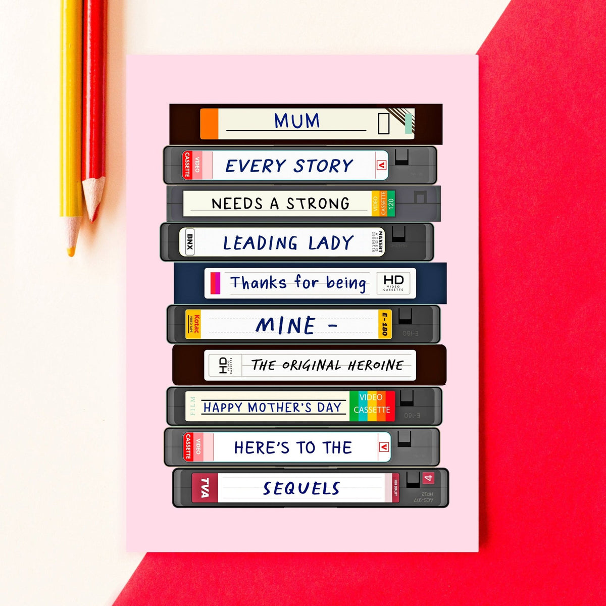 a mother's day card depicting a stack of cassettes with a message about how mum is the original heroine. Perfect for movie loving mums, the card is pictured on a red background