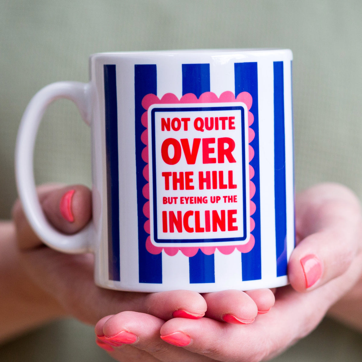 Mug with blue and white striped design and humorous text held by a person.