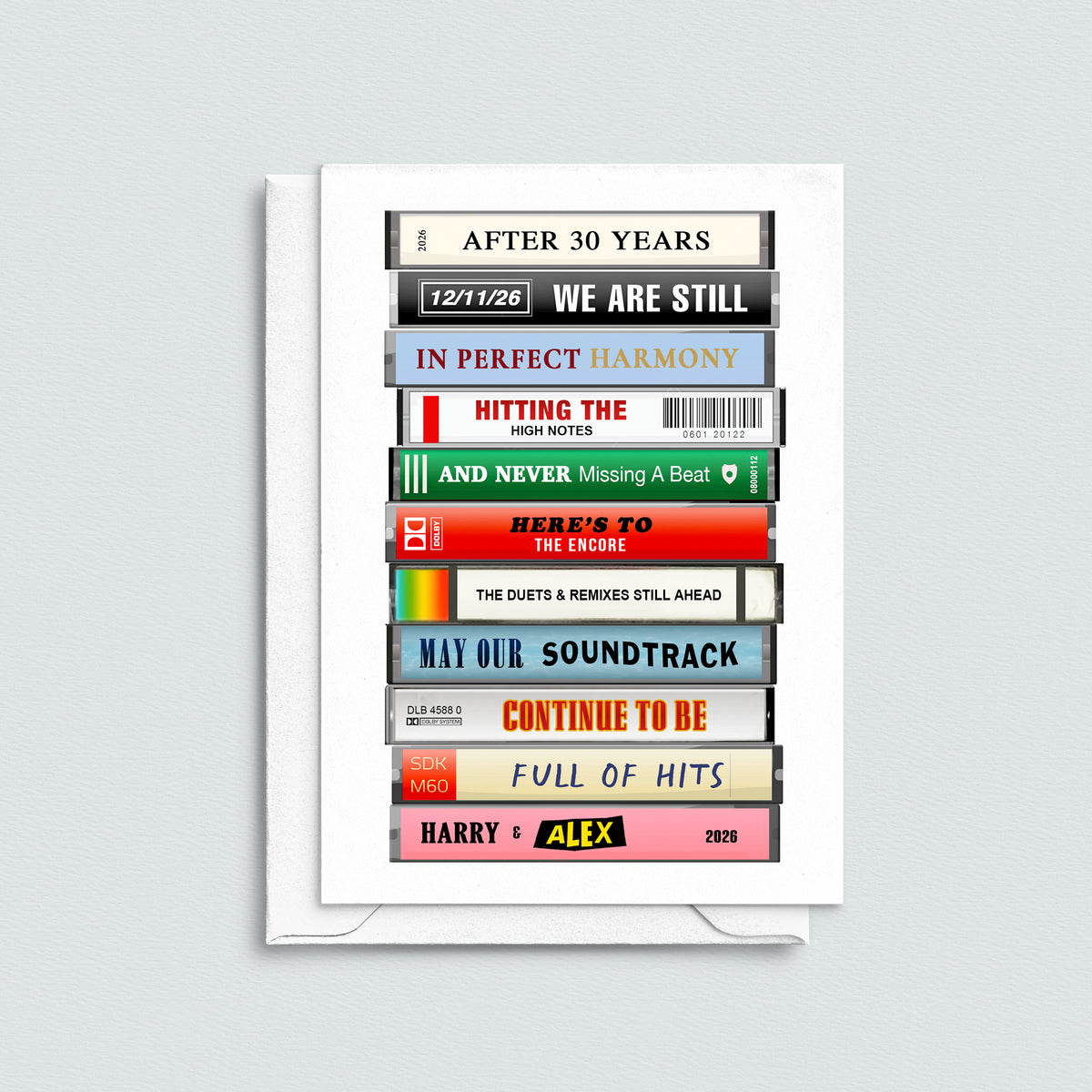 A white greeting card with a printed collage of cassette tape covers in various colors and song titles, displayed against a light gray background.