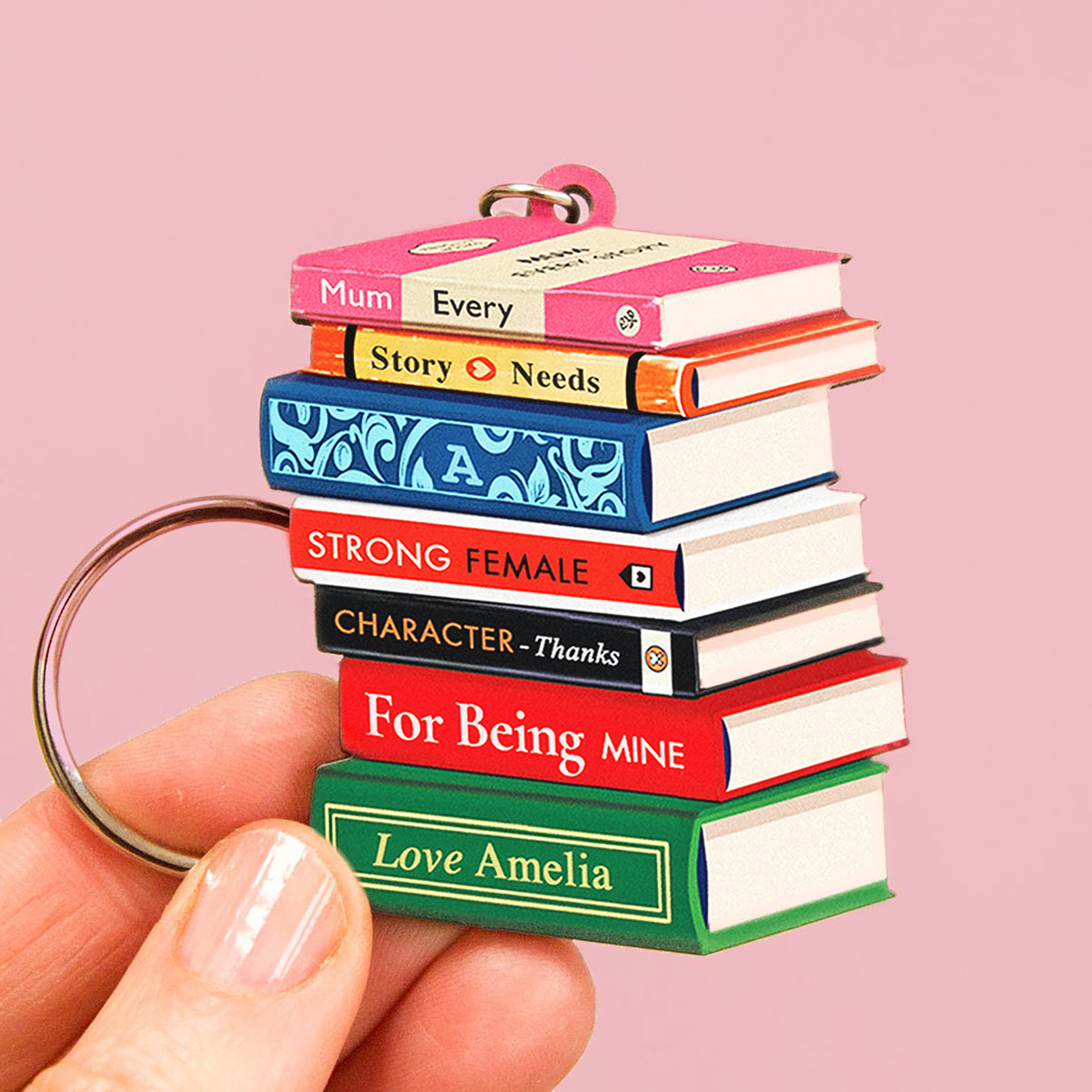 Stack of miniature books keychain with personalised text for Mum on a pink background