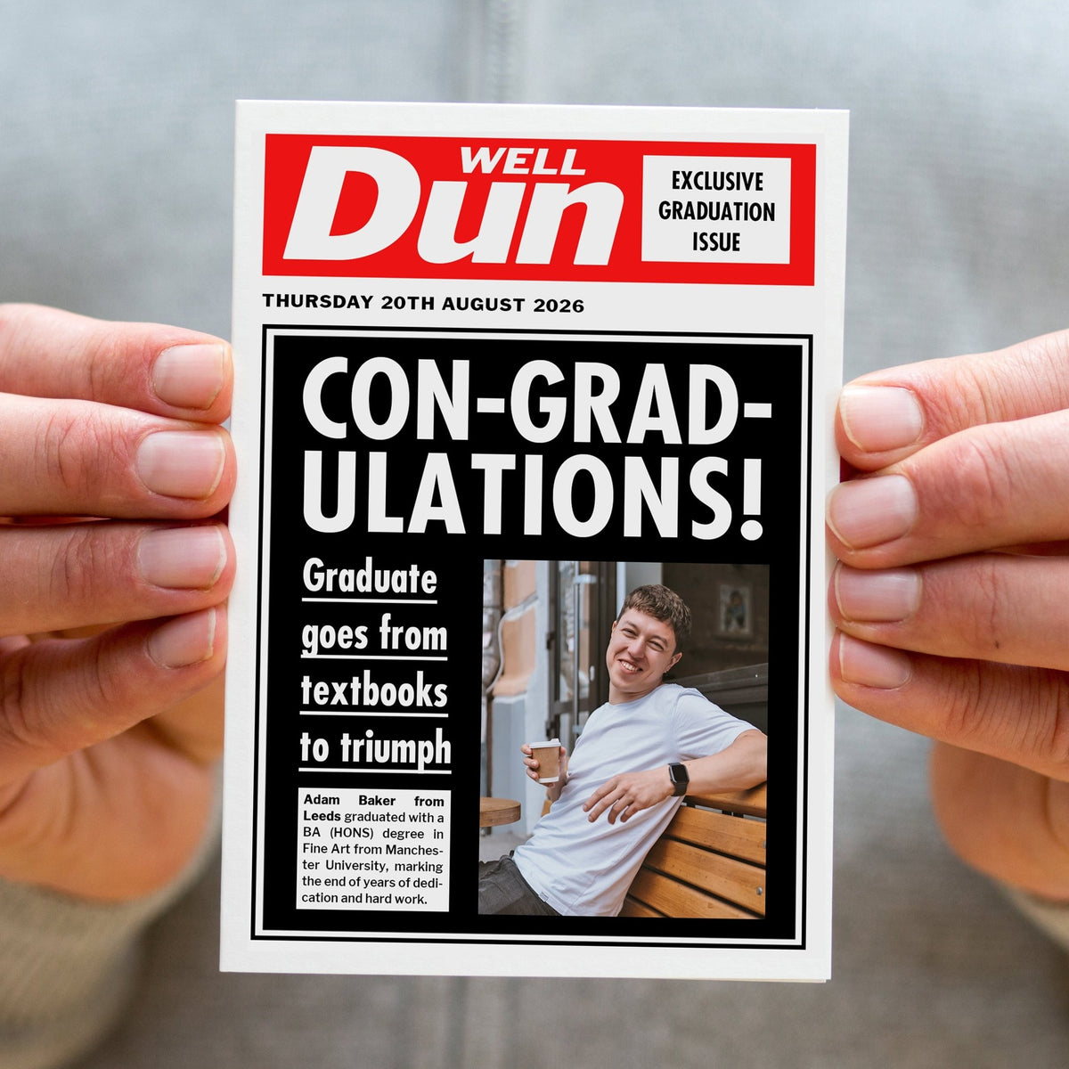 Person holding a ;personalised greeting card designed to look like a newspaper with a graduation-themed front page.